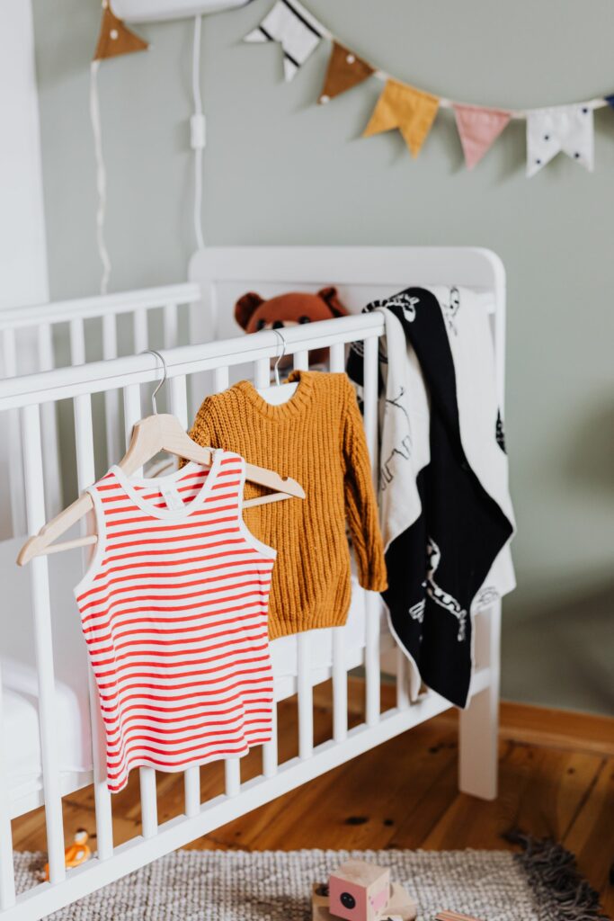 Vêtements de bébé suspendus près du lit